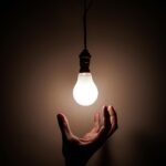 a hand reaching up to a lightbulb