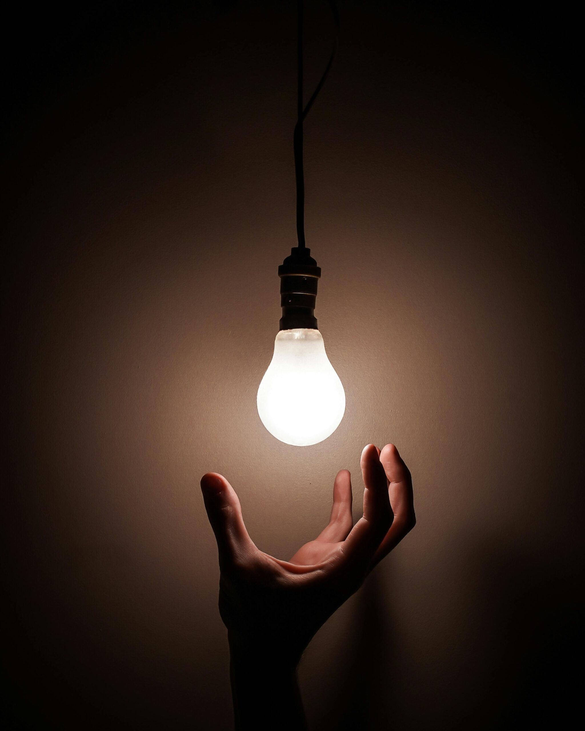 a hand reaching up to a lightbulb